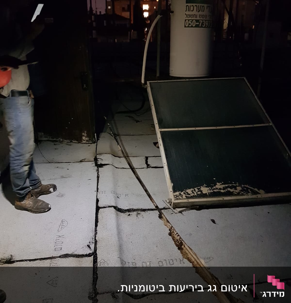 גג עם יריעות איטום וסדקים, אדם מחזיק טלפון
